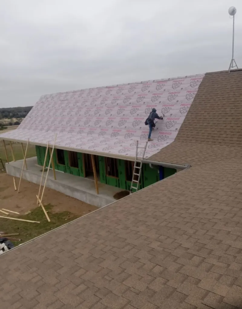 Worker preparing underlayment for a metal roof installation in Arizona City